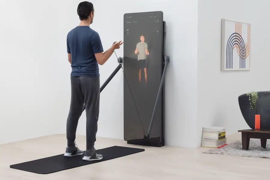 Smart fitness mirror with a person performing bicep curls, demonstrating the advanced features of interactive home workout equipment.