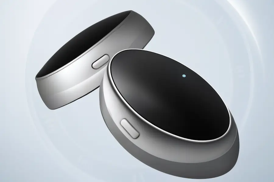 Two sleek Z3 Pro anti-snoring smart rings with brushed silver-gray and matte black finish, featuring blue LED lights, placed against a soft, cool-toned clock face background.